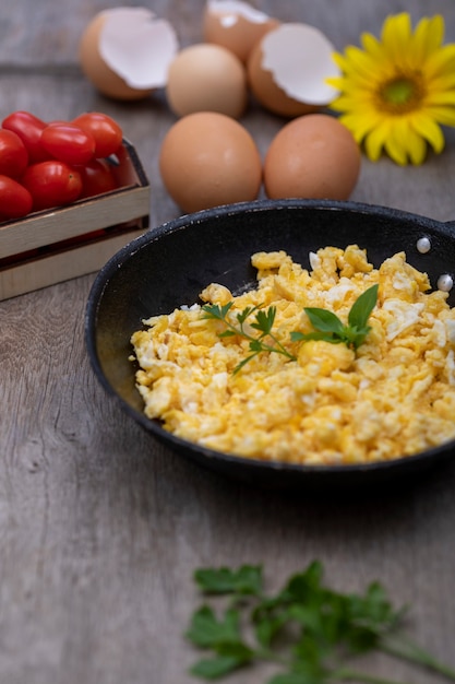 Huevos revueltos en una sartén de hierro sobre la mesa de madera rústica