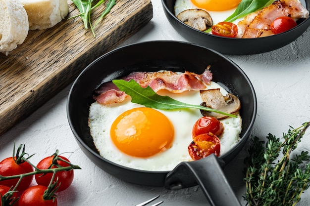 Huevos revueltos en una sartén con manteca de cerdo, pan y plumas verdes en una sartén de hierro fundido, sobre fondo blanco.