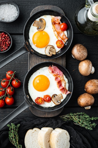 Huevos revueltos en una sartén con manteca de cerdo, pan y plumas verdes en una sartén de hierro fundido, sobre fondo de mesa de madera negra, vista superior plana