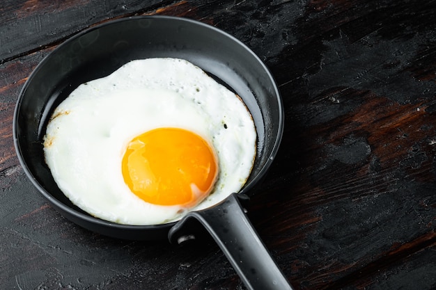 Huevos revueltos en una sartén con manteca de cerdo, pan y plumas verdes en una sartén de hierro fundido, sobre la vieja mesa de madera oscura, fondo