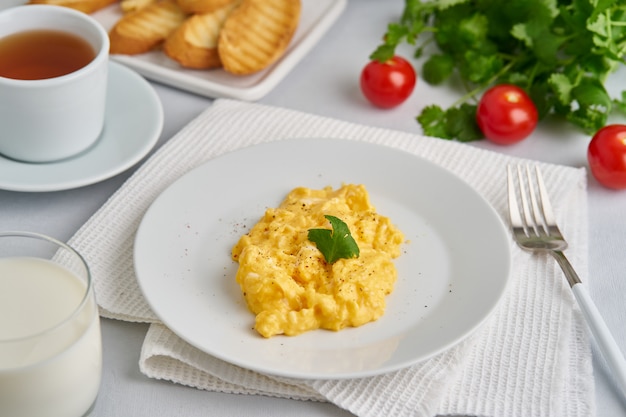 Huevos revueltos, tortilla, vista lateral. Desayuno con huevos fritos, vaso de leche.