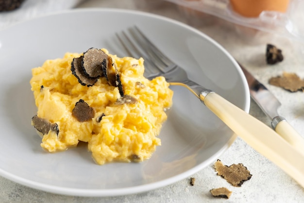 Huevos revueltos con trufas negras frescas de Italia servidos en un plato cerca del desayuno gourmet