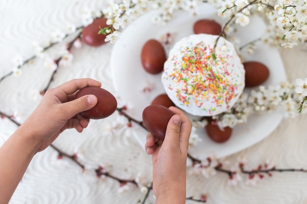 Huevos rojos para Pascua, menú tradicional de Pascua, manos sosteniendo huevos pintados.