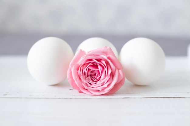 Huevos con una rosa rosa sobre una mesa blanca