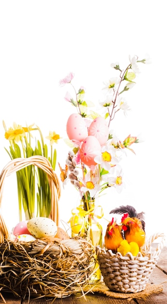 Huevos rosados y amarillos en la canasta, decoraciones de Pascua sobre fondo blanco.