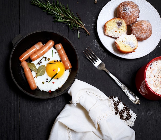 Huevos con salchichas en una sartén negra.