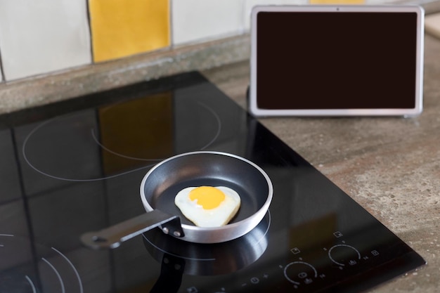 Huevos en una sartén en forma de corazón y una pantalla de tableta con un lugar para copiar Enfoque selectivo