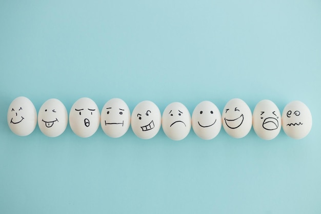 Huevos sonrientes y tristes sobre un fondo azul.