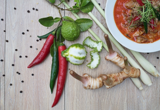 Huhn Massaman Curry und andere Bestandteile auf hölzernem Hintergrund.