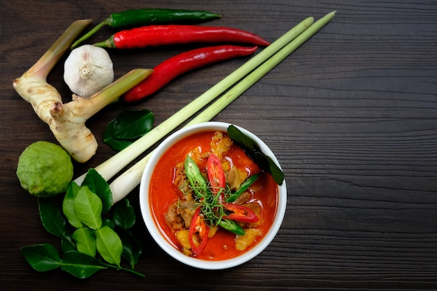 Huhn Massaman Curry und andere Bestandteile auf hölzernem Hintergrund.