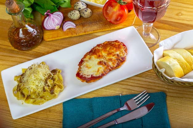 Foto huhn parmigiana und spaghettis nah oben auf einer platte auf dem tisch.