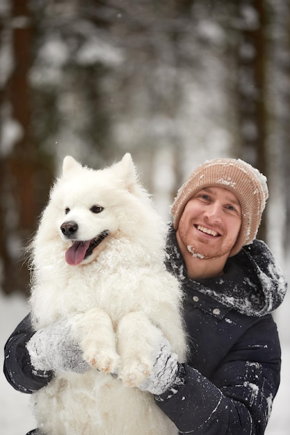 Un humano y un perro son los mejores amigos El hombre y el perro caminan en un bosque nevado en invierno en la nieve profunda en un día soleado