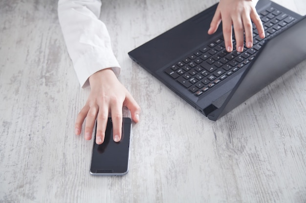 Humanos usando un teléfono inteligente y trabajando en una computadora.