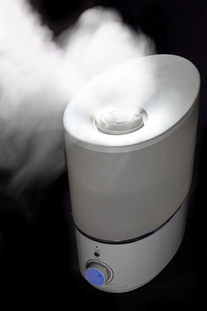 Foto humidificador esparciendo vapor en una habitación oscura