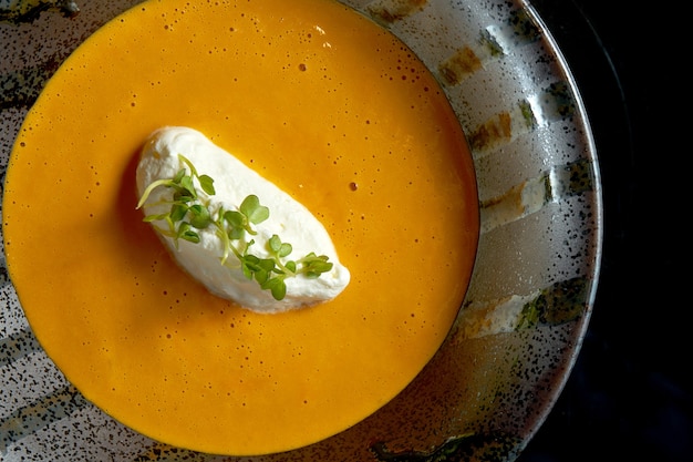 Hummercremesuppe mit Frischkäse in einer schwarzen Schüssel lokalisiert auf einem schwarzen Hintergrund.