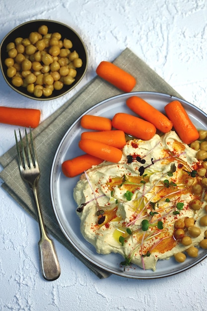 Hummus con aceite de oliva y zanahorias baby en un plato