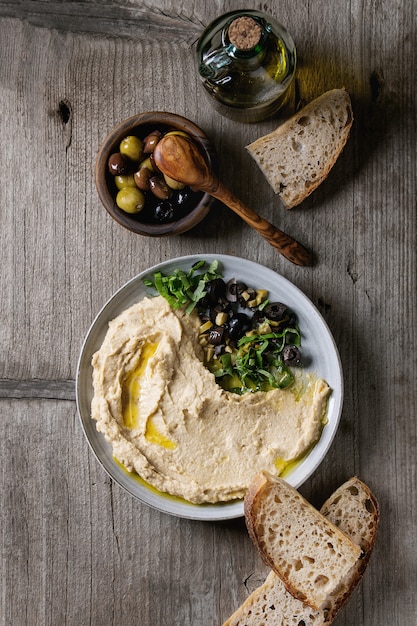 Foto hummus con aceitunas y hierbas.