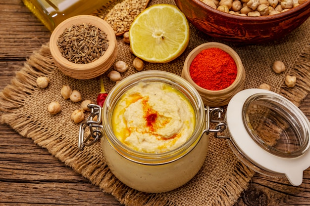 Hummus auf altem Holztisch. Trockene Kichererbsen, Olivenöl, Zitrone, Kreuzkümmel und Chili