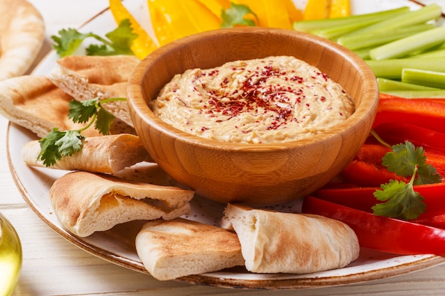 Hummus casero saludable con una variedad de verduras frescas y pan de pita.