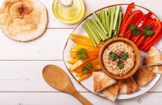 Hummus casero saludable con una variedad de verduras frescas y pan de pita.