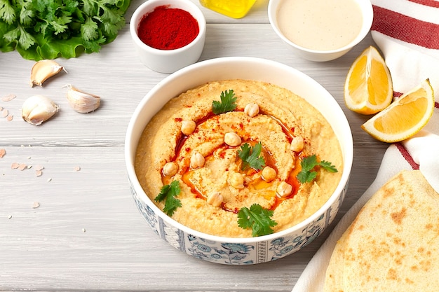 Hummus clássico de grão de bico com tahine, azeite, alho e páprica, caseiro, sobre um fundo branco, vista de cima, sem pessoas. Foto de alta qualidade