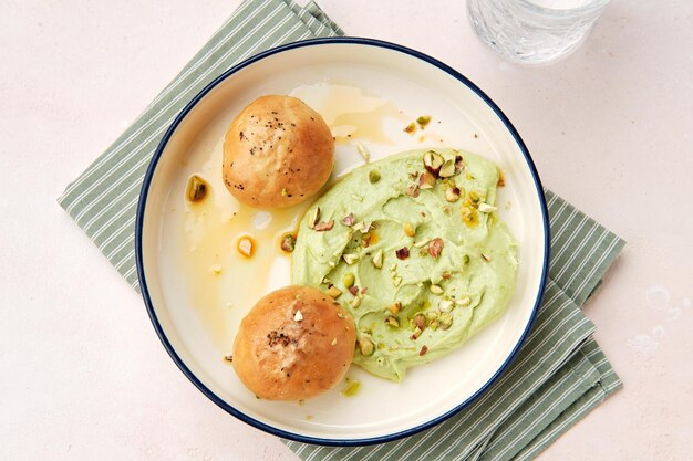 Hummus com dois bolinhos de alho em um belo prato branco adornado com nozes picadas cozinha listrada