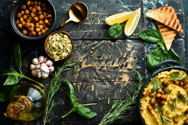 Hummus com grão-de-bico e alecrim em um prato de pedra preta comida vegetariana vista de cima em um fundo de pedra preta