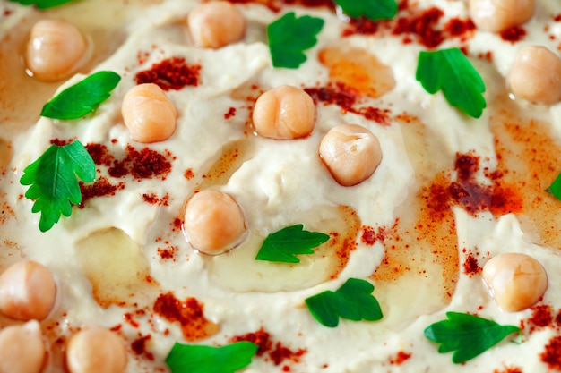 Hummus com grãos de grão de bico pimenta vermelha azeite e salsa verde closeup foco seletivo xA