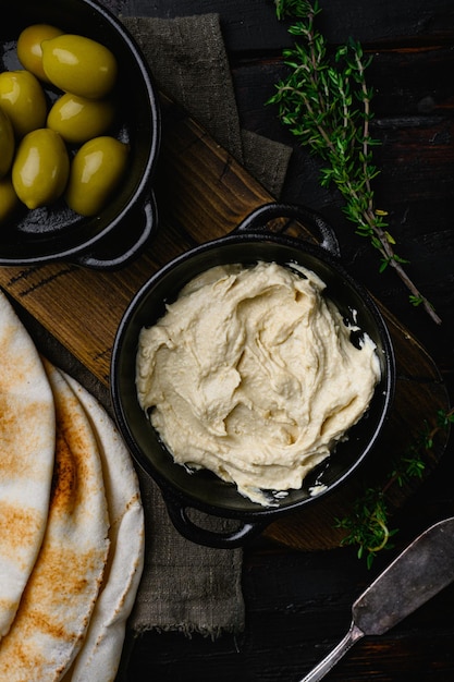 Hummus cremoso caseiro saudável colocado na velha mesa de madeira escura, vista superior plana