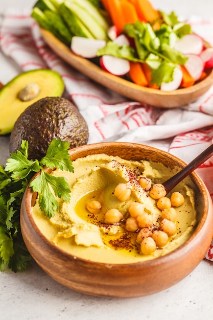 Hummus do abacate em uma bacia de madeira com vegetais.