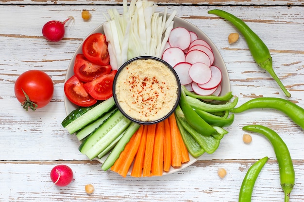 Hummus em tigela, palitos de legumes, grão de bico, azeitonas.