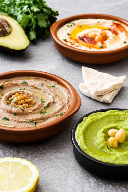 Hummus de garbanzos, hummus de aguacate y hummus de lentejas sobre piedra gris