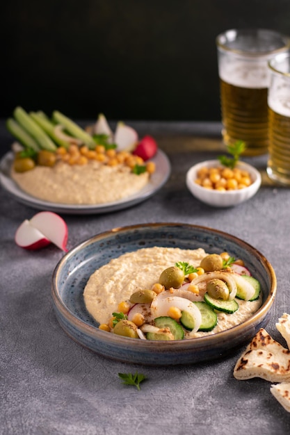 Hummus Große Schüssel mit hausgemachtem Hummus, garniert mit Kichererbsen, roter Paprika, Petersilie und Olivenöl, flach gelegtes Essen aus dem Nahen Osten