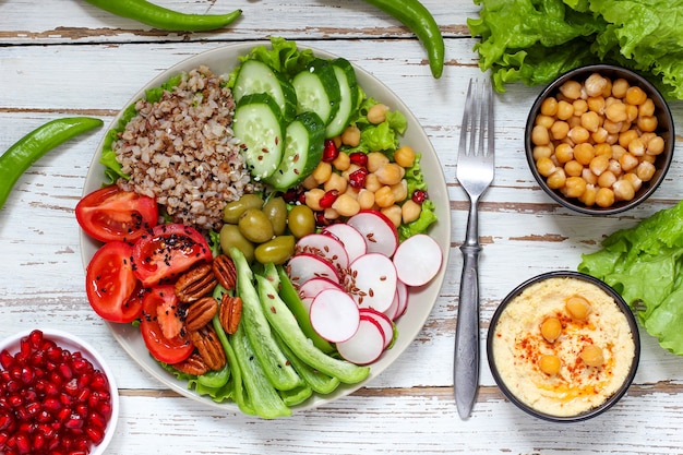 Hummus in Schüssel, Gemüsesticks, Kichererbsen, Oliven.