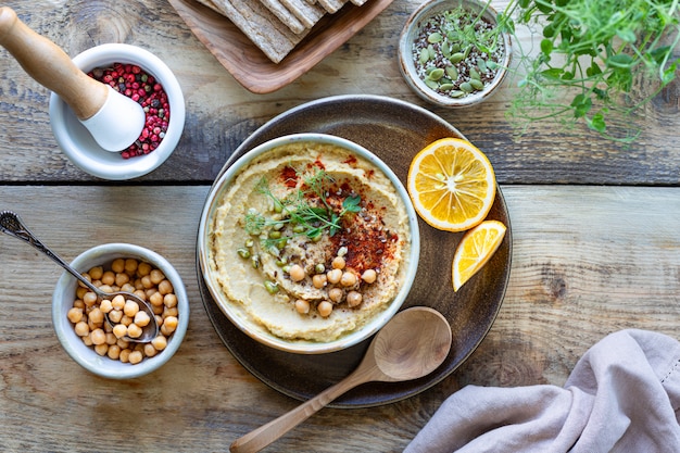 Hummus, Kichererbsensauce mit geräuchertem Paprika-Olivenöl in einer Keramikschale auf einem hölzernen Hintergrund. Draufsicht.