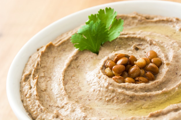 Foto hummus de lentejas en un tazón sobre madera de cerca