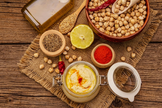 Hummus en la mesa de madera vieja. Garbanzos secos, aceite de oliva, limón, comino y ají