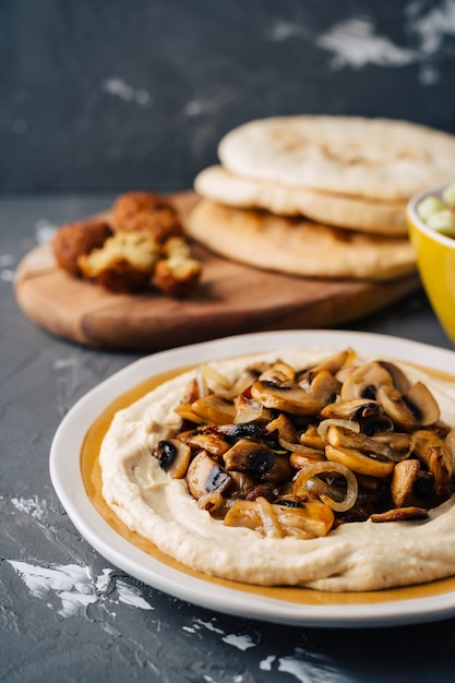 Hummus mit gebratenem Hummus mit gebratenen Pilzen, Gurken-Tomaten-Salat, Falafel und Pita.