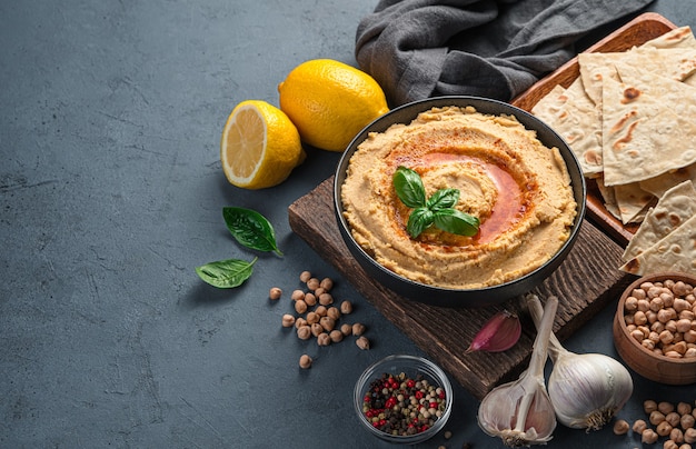 Hummus mit Olivenöl und Paprika auf dem Hintergrund der Zutaten