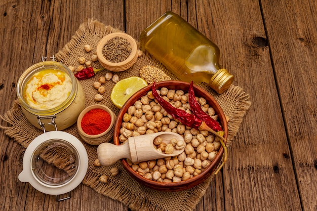 Hummus na mesa de madeira velha. Grão de bico seco, azeite, limão, cominho e pimenta