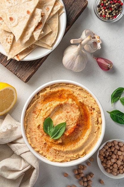 Hummus oriental e ingredientes sobre una vista superior de fondo gris vertical