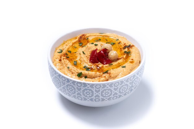 Hummus de pimiento rojo asado en un recipiente blanco aislado sobre fondo blanco.