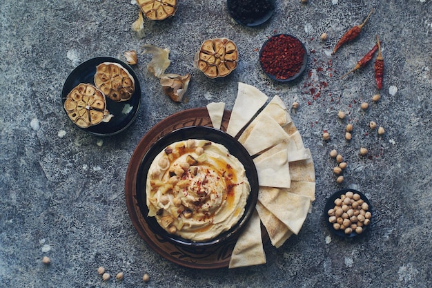 Hummus de plato casero tradicional del medio oriente decorado con garbanzos y ajo