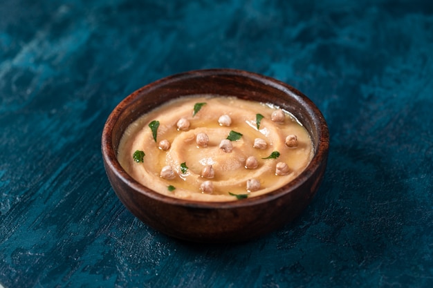 Hummus en un plato de madera marrón.