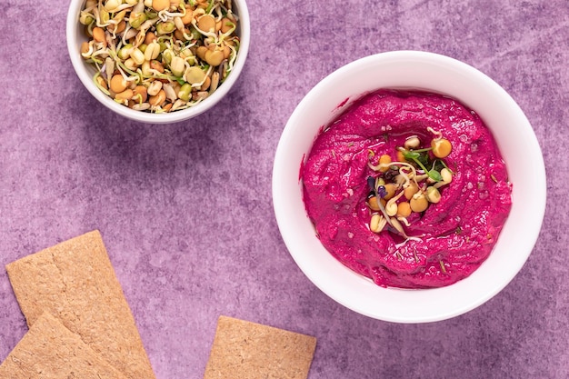 Foto hummus de remolacha asada con granos germinados y vista superior de pan crujiente