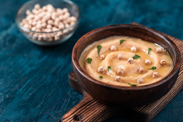 Hummus en un tazón de madera marrón.