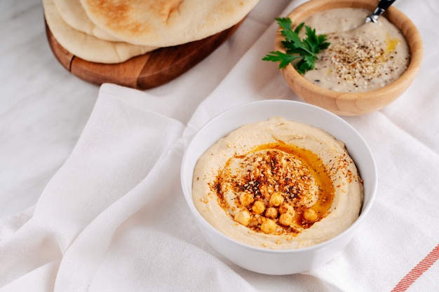 Hummus und Baba Ghanoush in einer Schüssel und Fladenbrot auf einem hellen Hintergrund.