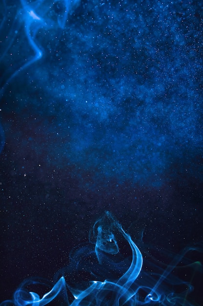 Foto humo azul y spray de agua sobre un fondo negro