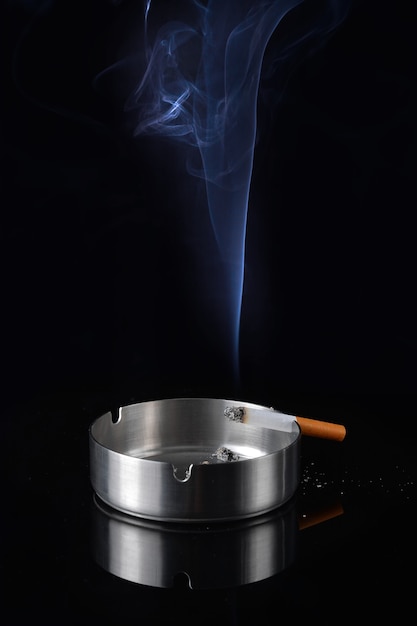Foto humo de un cigarrillo en un cenicero