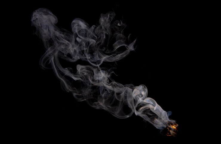 un humo es visible desde una pipa que tiene un fondo negro